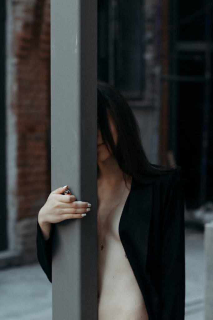 mysterieuse Ines A mysterious portrait of a woman partially hidden behind a pole in an urban setting.
